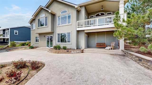 rear view of house featuring a patio, a balcony, and stucco siding