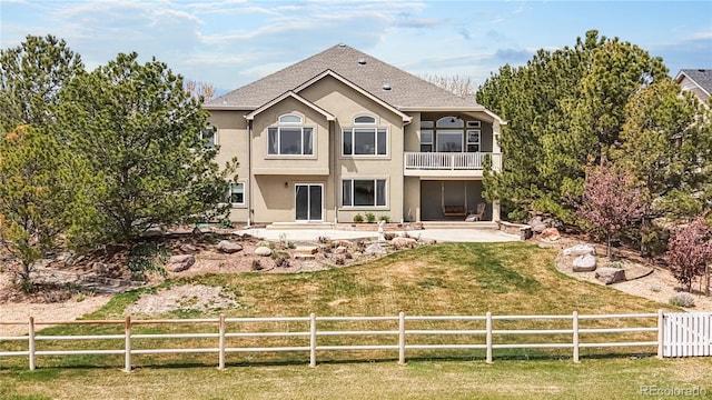 back of house with stucco siding, fence private yard, a patio area, and a balcony