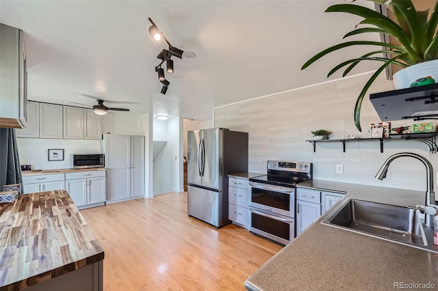 kitchen featuring open shelves, ceiling fan, a sink, stainless steel appliances, and butcher block counters