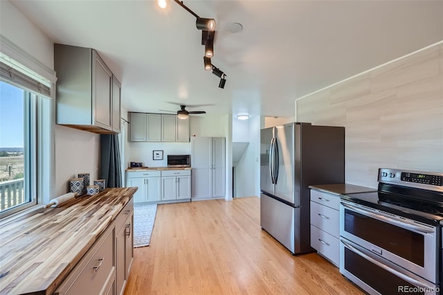 kitchen with gray cabinetry, light hardwood / wood-style floors, stainless steel appliances, wooden counters, and ceiling fan