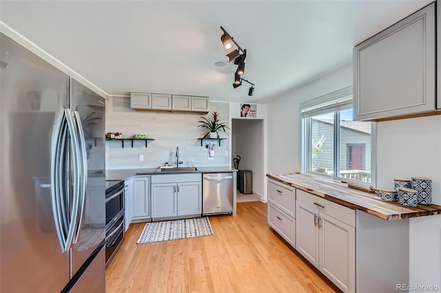 kitchen with gray cabinets, sink, butcher block counters, light hardwood / wood-style flooring, and appliances with stainless steel finishes