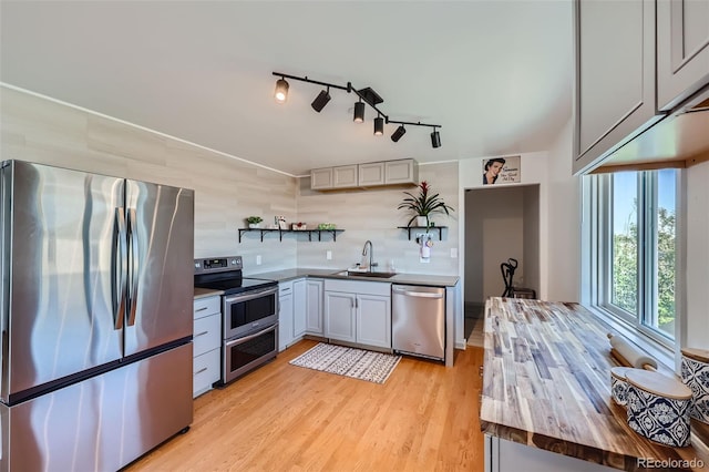 kitchen featuring sink, light hardwood / wood-style flooring, gray cabinets, stainless steel appliances, and wood counters