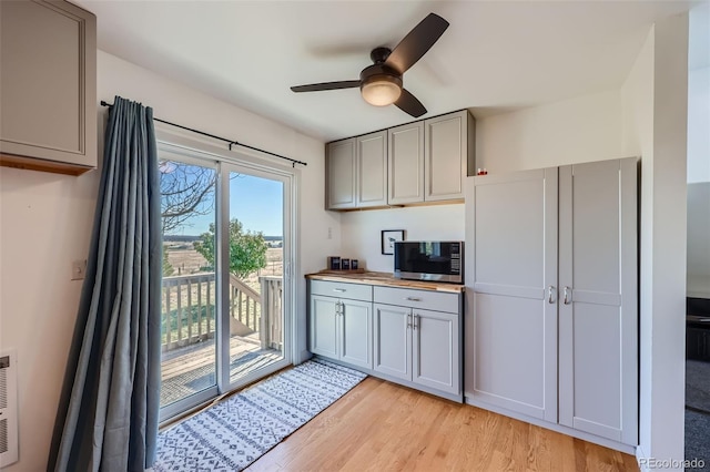 kitchen featuring ceiling fan, gray cabinetry, stainless steel microwave, light wood finished floors, and butcher block counters