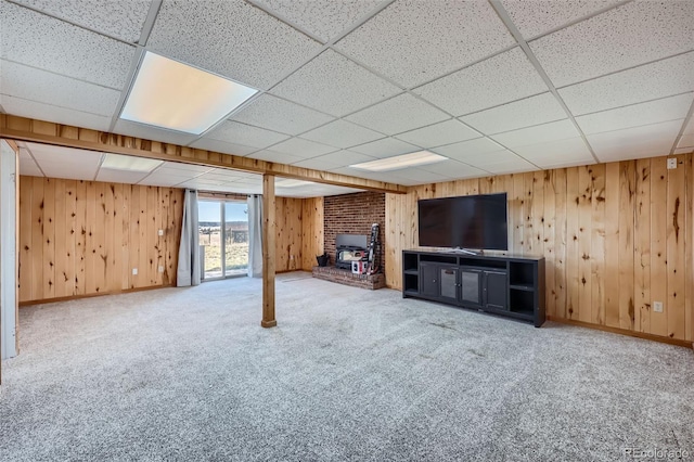 unfurnished living room with carpet floors, a drop ceiling, and wood walls