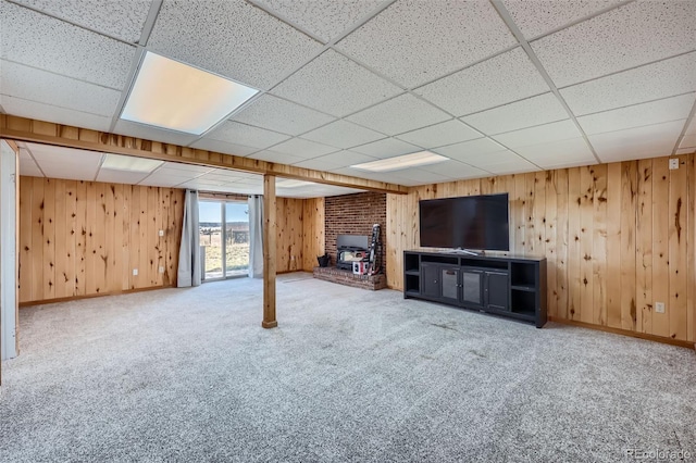 below grade area with carpet floors, a drop ceiling, and wooden walls