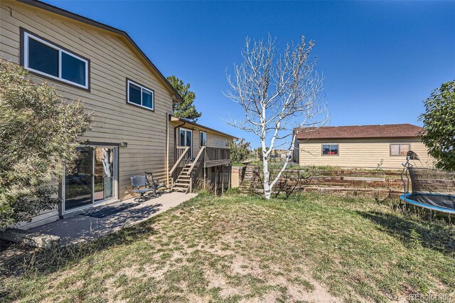 view of yard featuring fence, a trampoline, a patio area, and stairway