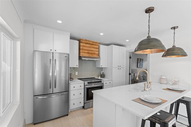 kitchen featuring a breakfast bar, white cabinetry, decorative light fixtures, appliances with stainless steel finishes, and kitchen peninsula