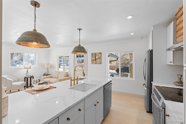 kitchen with sink, gray cabinetry, appliances with stainless steel finishes, pendant lighting, and light stone countertops