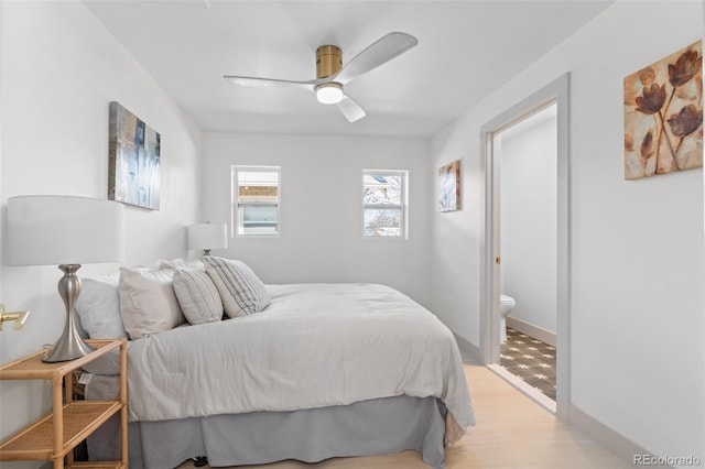 bedroom with ceiling fan, ensuite bath, and light wood-type flooring