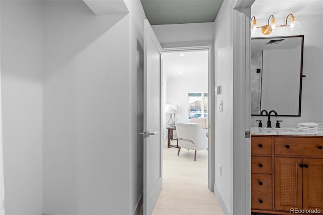 hallway with sink and light hardwood / wood-style flooring