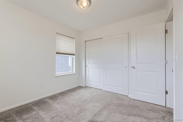 unfurnished bedroom with light carpet and a closet