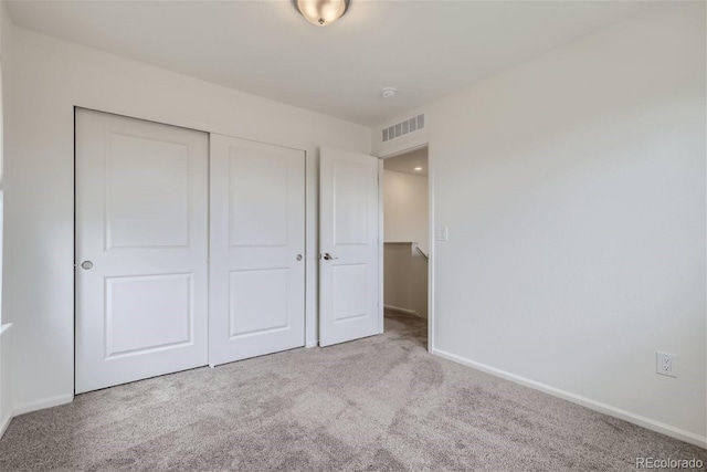 unfurnished bedroom with light colored carpet and a closet