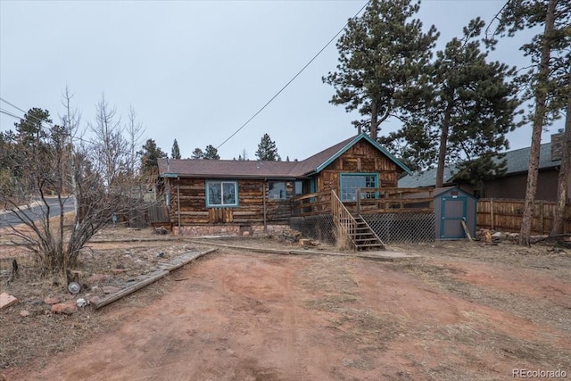 back of house featuring a storage shed and a wooden deck