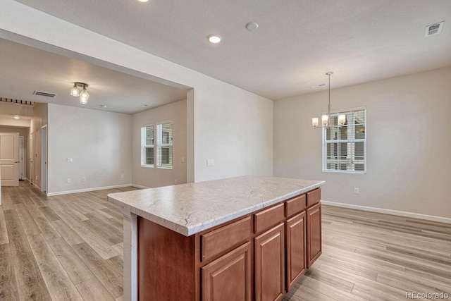 kitchen with a kitchen island, hanging light fixtures, light wood-type flooring, and a chandelier