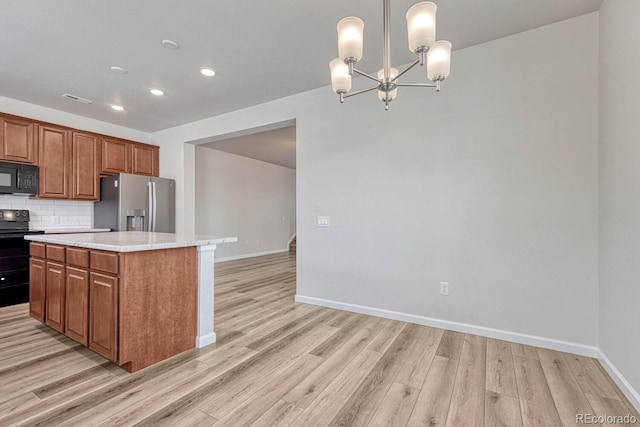 kitchen with black appliances, light hardwood / wood-style flooring, a chandelier, and hanging light fixtures