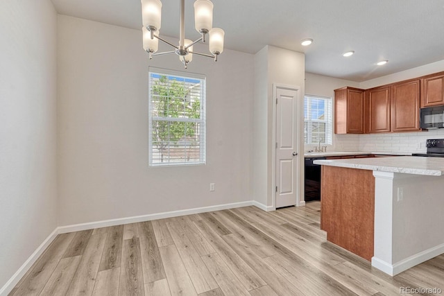 kitchen with light wood-type flooring, black appliances, a wealth of natural light, and hanging light fixtures