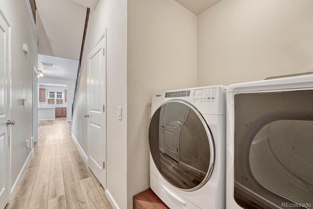 laundry room featuring light wood-type flooring and washer and clothes dryer