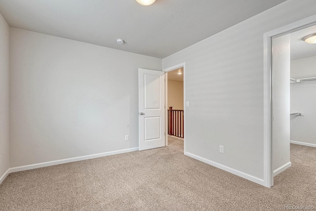 unfurnished bedroom with a closet, carpet flooring, and a spacious closet