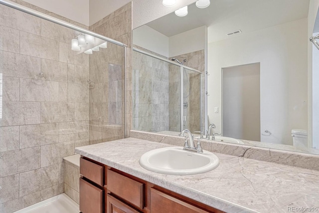 bathroom featuring vanity, toilet, and a shower with door