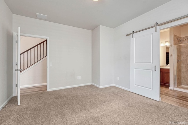 spare room with a barn door and carpet