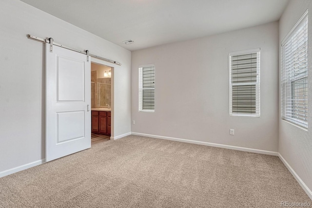 spare room featuring a barn door, a healthy amount of sunlight, and carpet floors