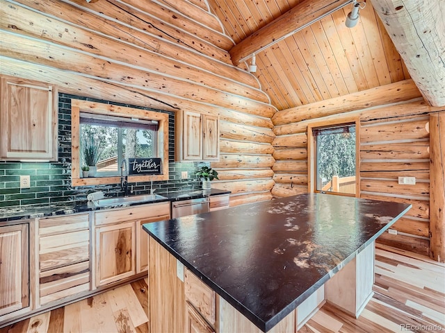 kitchen with light brown cabinetry, sink, backsplash, and a center island