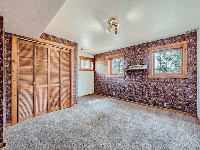 unfurnished bedroom featuring carpet, a textured ceiling, and a closet