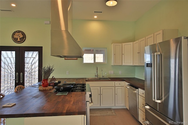 kitchen featuring wood counters, french doors, ventilation hood, sink, and stainless steel appliances