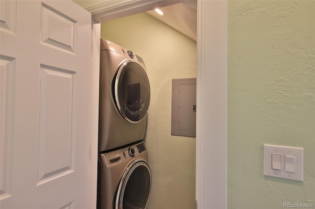 laundry room with electric panel and stacked washing maching and dryer
