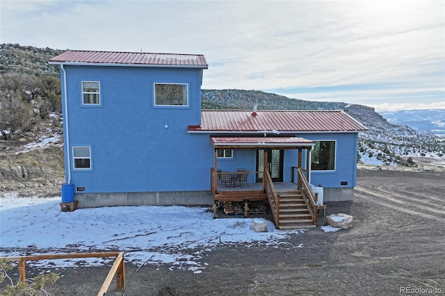 snow covered back of property featuring a mountain view
