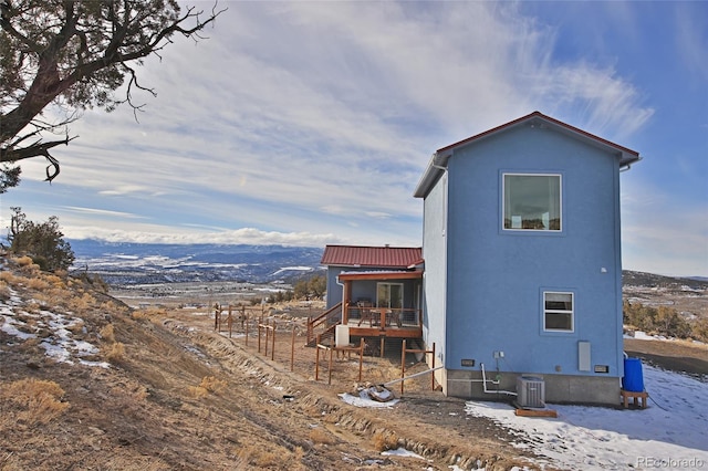snow covered property featuring a mountain view and central AC unit