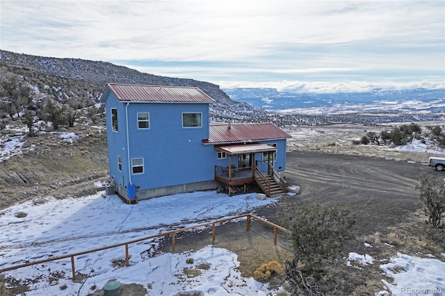 snow covered property with a deck with mountain view