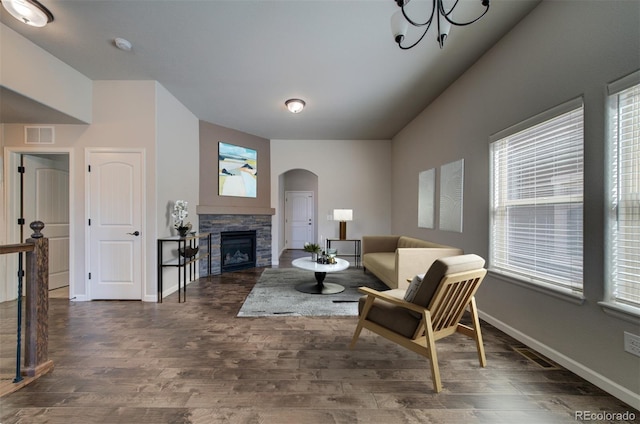 living room featuring a stone fireplace and dark wood-type flooring