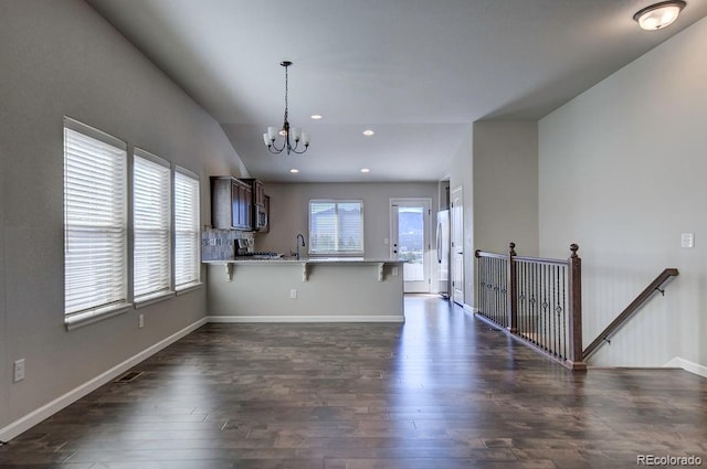 kitchen with dark hardwood / wood-style floors, a kitchen breakfast bar, kitchen peninsula, stainless steel appliances, and vaulted ceiling