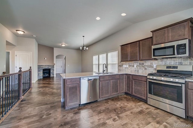 kitchen featuring a stone fireplace, dark wood-type flooring, stainless steel appliances, and sink