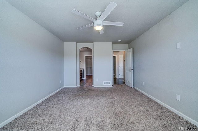 unfurnished bedroom featuring a spacious closet, carpet, and ceiling fan