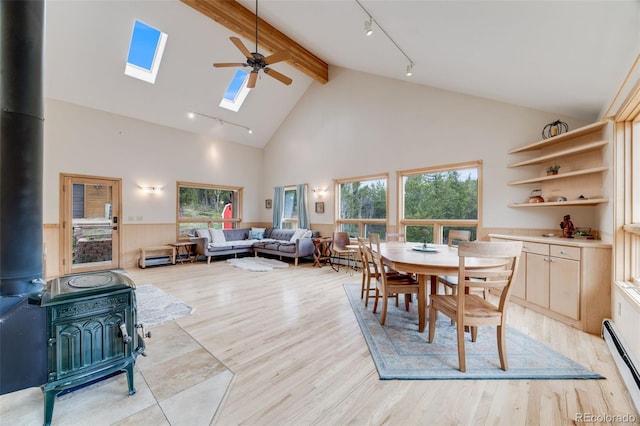 1002 County Road 99, Black Hawk, CO 80422 - dining area featuring a wood stove, rail lighting, a baseboard radiator, beam ceiling, and high vaulted ceiling
