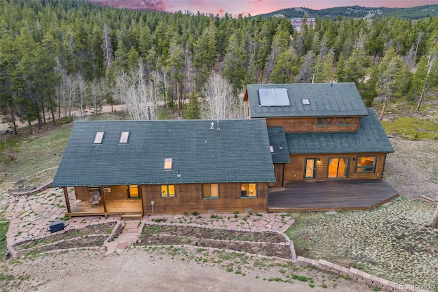 1002 County Road 99, Black Hawk, CO 80422 - back of house featuring a porch, a wooded view, and roof with shingles