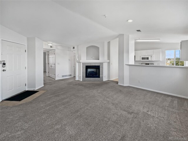 6850 Xavier Cir Unit 12, Westminster, CO 80030 - unfurnished living room with carpet flooring, vaulted ceiling, baseboards, and a tile fireplace