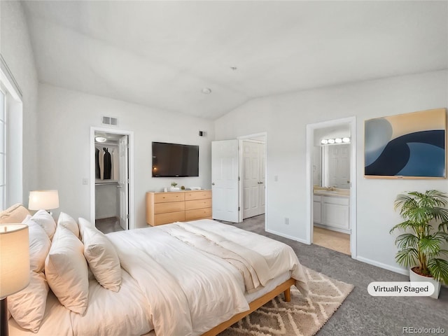 bedroom featuring carpet flooring, connected bathroom, vaulted ceiling, a walk in closet, and a closet