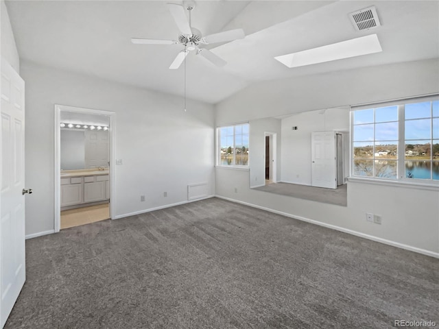 unfurnished bedroom featuring connected bathroom, a water view, multiple windows, and vaulted ceiling with skylight