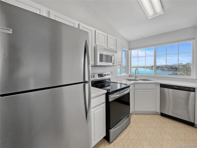 kitchen with lofted ceiling, a water view, sink, appliances with stainless steel finishes, and white cabinetry