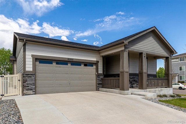 10595 Boston St, Commerce City, CO 80640 - view of front of property with stone siding, a porch, driveway, and a garage