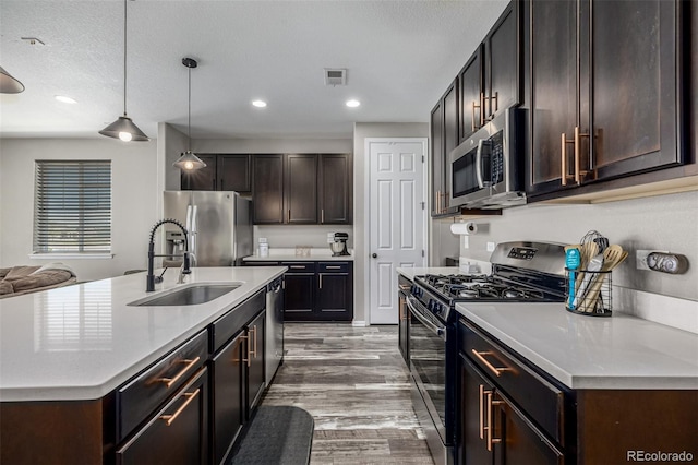 10595 Boston St, Commerce City, CO 80640 - kitchen with appliances with stainless steel finishes, a sink, light wood-type flooring, dark brown cabinetry, and light countertops