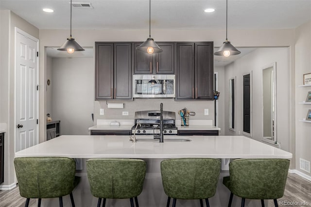 10595 Boston St, Commerce City, CO 80640 - kitchen featuring appliances with stainless steel finishes, a sink, wood finished floors, a breakfast bar area, and recessed lighting