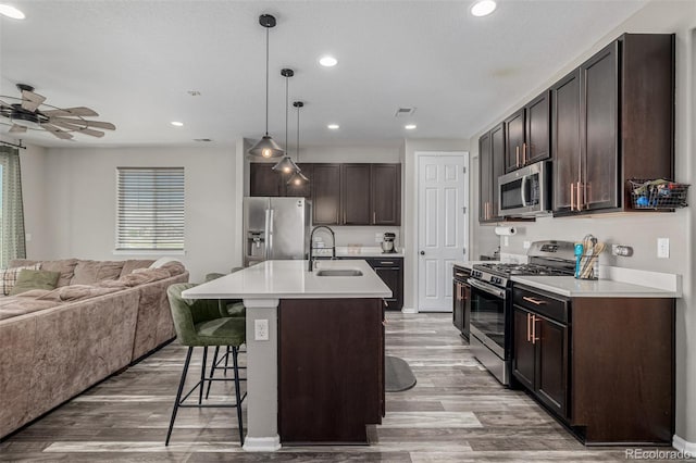 10595 Boston St, Commerce City, CO 80640 - kitchen featuring appliances with stainless steel finishes, a sink, open floor plan, dark brown cabinetry, and a breakfast bar area