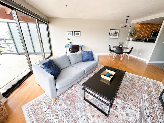 living room with light hardwood / wood-style flooring, a notable chandelier, and sink