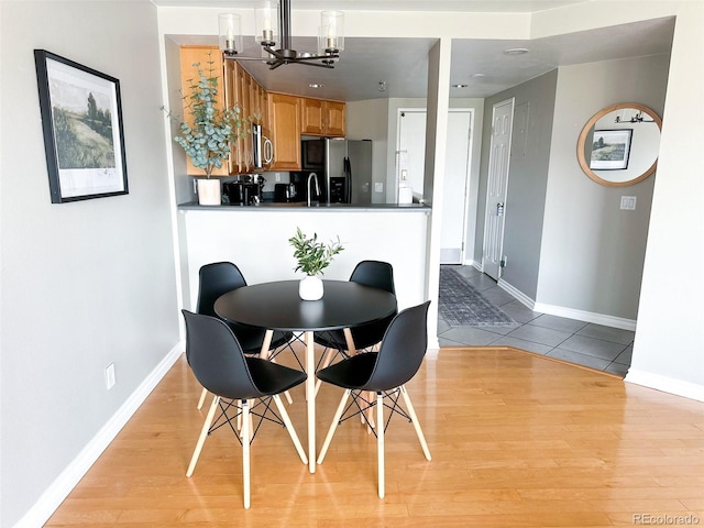 dining area with sink, a notable chandelier, and light hardwood / wood-style flooring