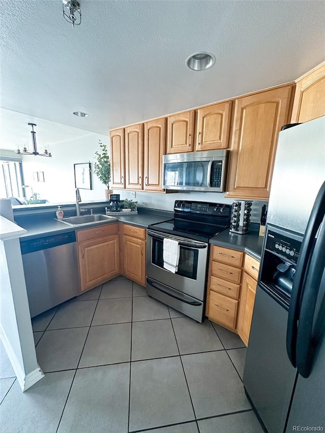 kitchen with a textured ceiling, stainless steel appliances, sink, and tile patterned floors