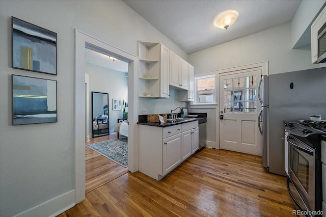 kitchen featuring appliances with stainless steel finishes, light wood-type flooring, sink, and white cabinetry